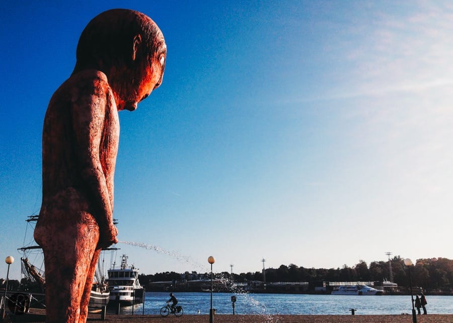 When we arrived in Helsinki in september 2014, we knew the city would show its weird side right away. It always happens to us when we travel. Maybe, we attract this kind of things but still don’t know why we attracted a huge pissing statue like the one we found on Helsinki’s harbor. Peeing in public is something our mothers didn’t want us to do. Sometimes it happens but we always hide somewhere so nobody can see what we are doing. But this statue is not hidden at all. It sits in the middle of Helsinki’s harbor next to where you catch the ferries to travel around the islands. Everywhere you look, you are going to see it. But, what is that?