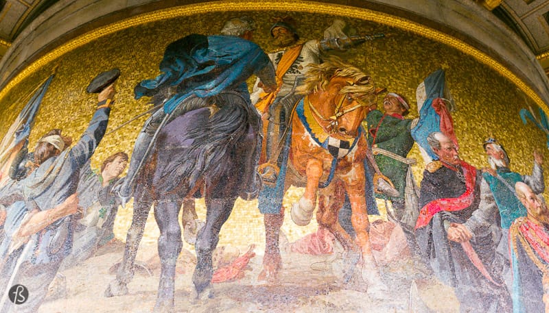 The golden sculpture on top of the column is made of bronze and weighs 35 tons, measuring a little over 8 meters. Friedrich Drake created the artwork; the statue was first intended to celebrate Prussia’s victory over Denmark in the Second Schleswig War in 1864. But, by the time it was finished, Prussia was celebrating victories in the Austro-Prussian War in 1866, and the Franco-Prussian War from 1870 to 1871. Those are known as the Wars of German Unification, and this is the story that you find in the mosaics and bronze reliefs around the base of the column.