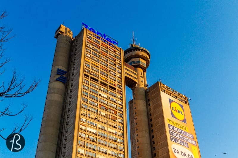 The building got the nickname Genex Tower since one of the towers was occupied but the Genex Group for years. Now, it's abandoned, but their Zepter logo can still be seen over the commercial side of the building. The smaller tower is a residential building with some shops on the ground floor and a few people passing by.